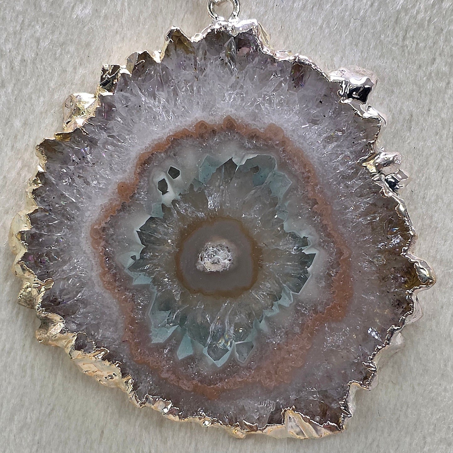 Geode pendant with silver setting on a light gray background