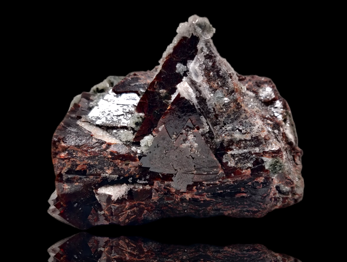 A polished mineral specimen featuring a crystal of helvine-genthelvite with quartz and calcite, with a label indicating the mineral name and origin.