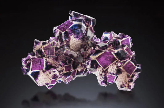 Close-up of a vibrant purple and beige crystal cluster with geometric shapes on a dark background