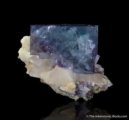 Clear cubic fluorite crystal with a purple hue on beige mineral matrix, premium gemstone display