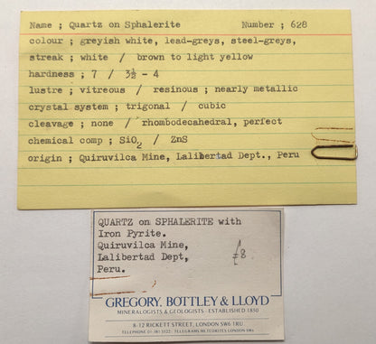 Yellowed card with text about quartz on sphalerite and a business card below.