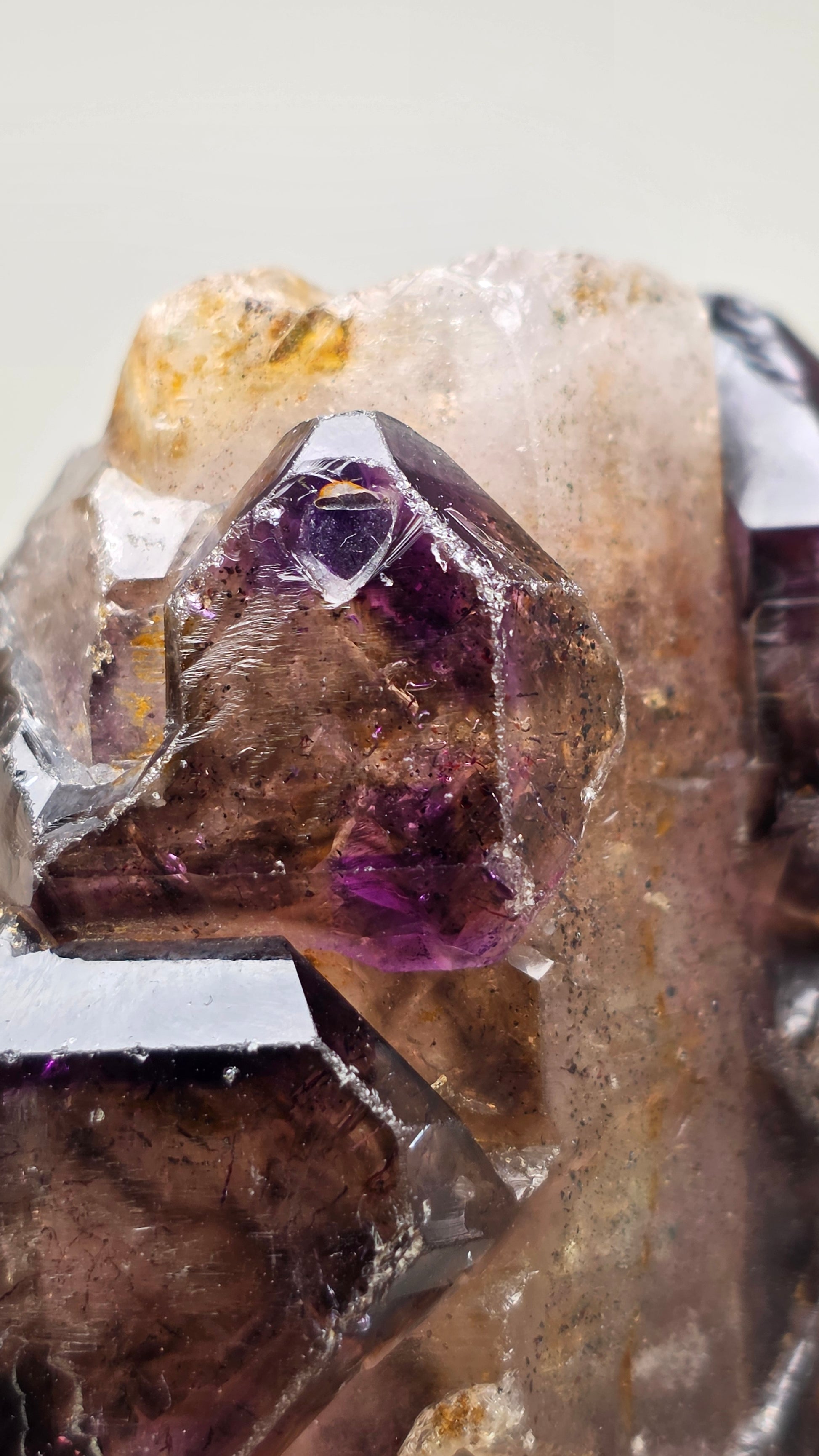 Close-up of a purple crystal with a clear mineral on a light background