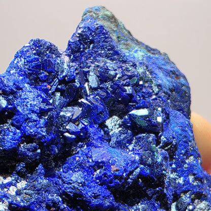 Close-up of a blue mineral crystal cluster on a beige background