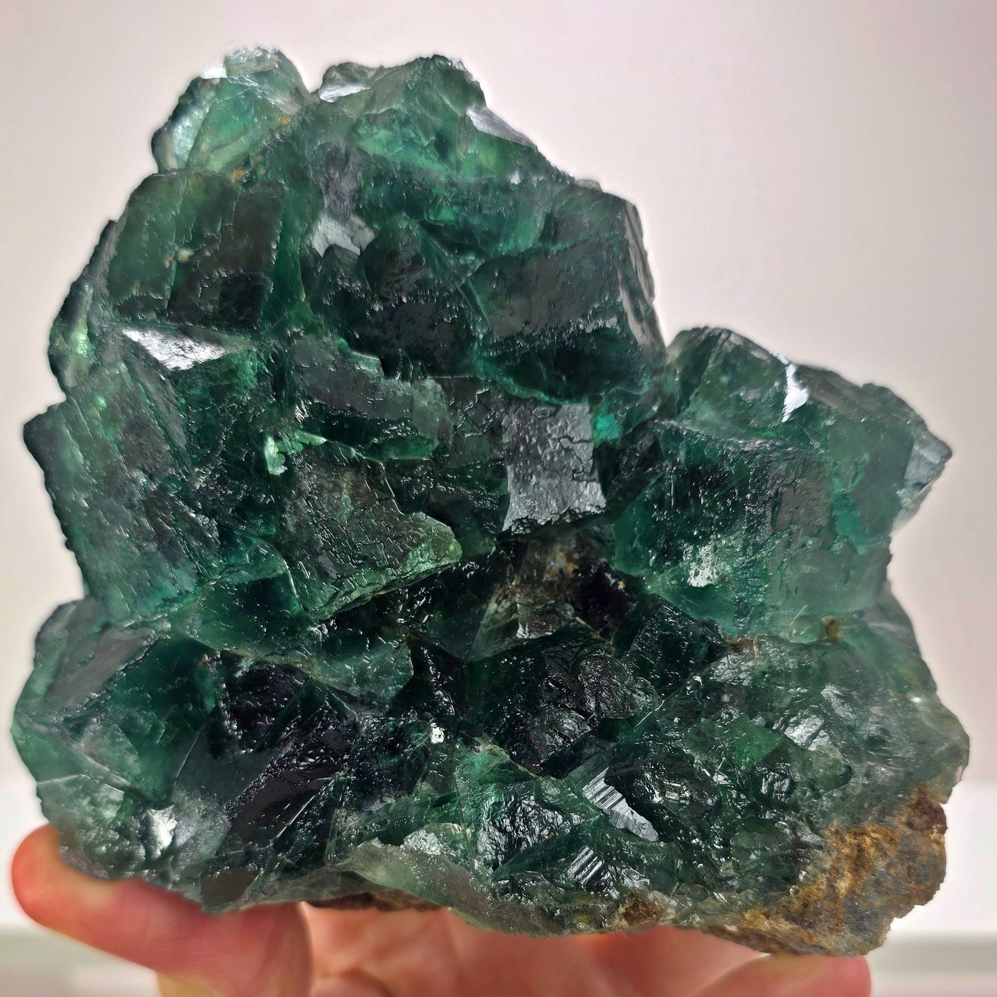 Green crystal rock held by a hand against a white background