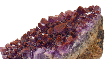 A natural amethyst crystal cluster with sharp purple and reddish-brown crystal points on a rough matrix, photographed against a plain light background.