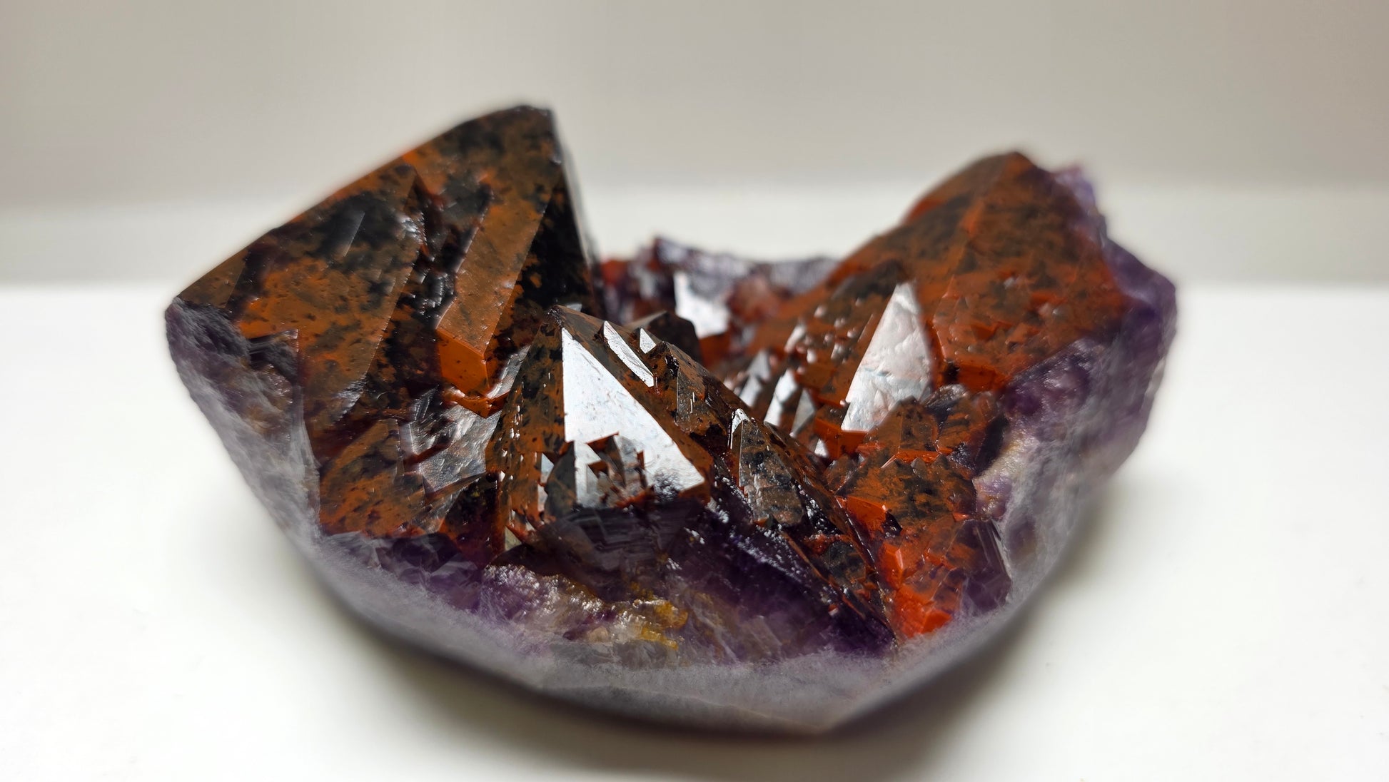 A natural crystal cluster specimen with prominent orange-brown and purple crystalline structures, photographed on a plain light background.