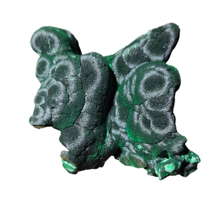 A hand holding a small, sculpted figurine of a frog made from textured green and black stone or resin with a mottled, organic pattern.