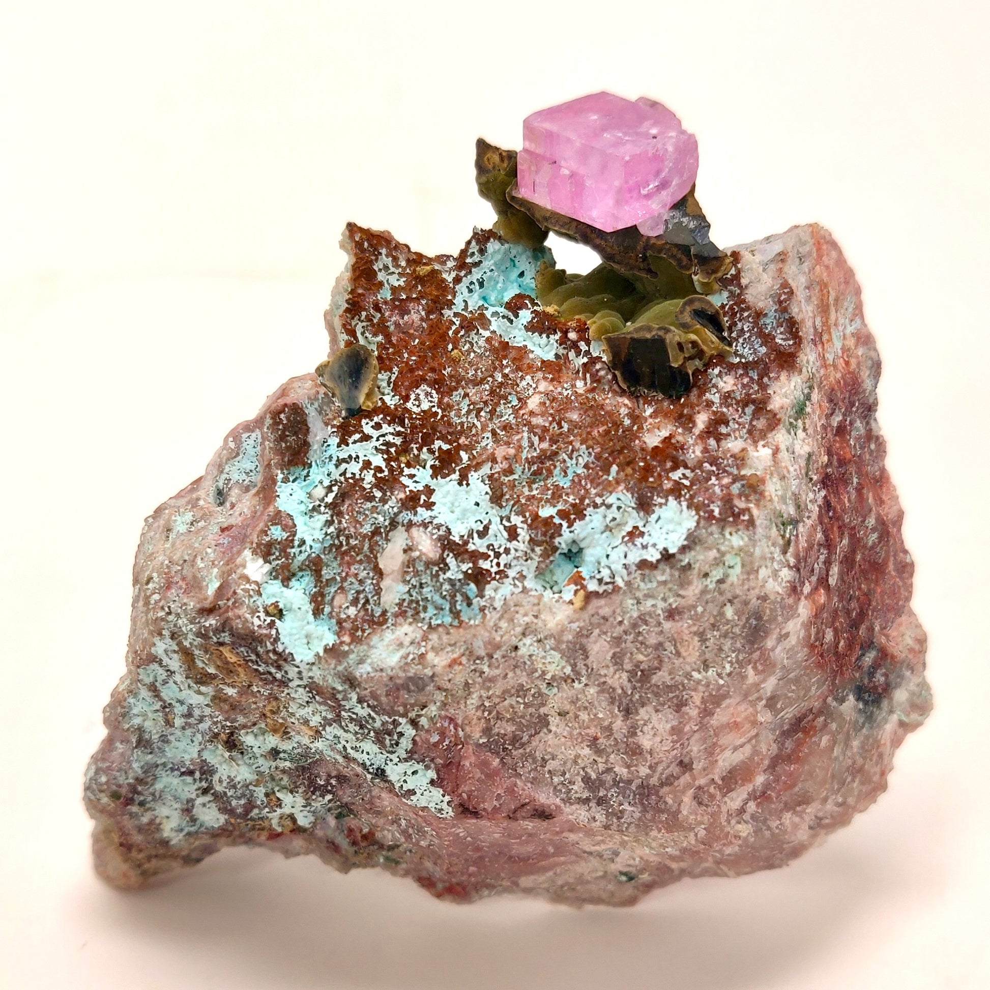 Mineral sample with a pink crystal on a rock against a white background