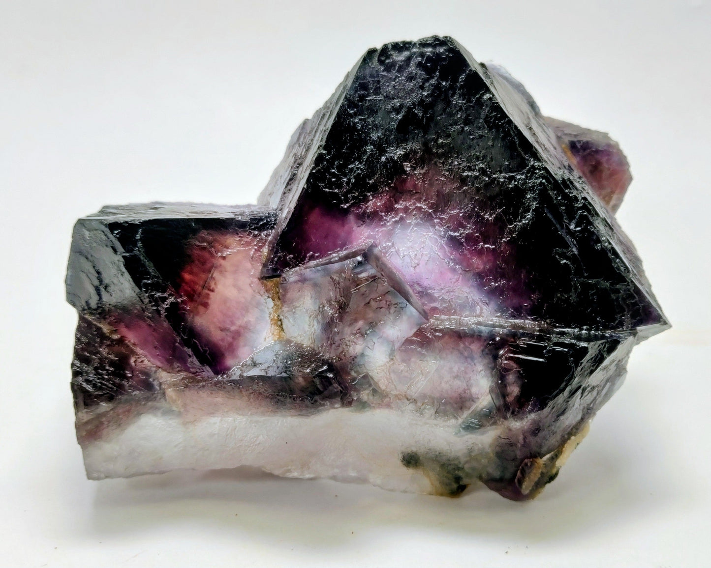 Mineral specimen with purple and black coloration on a white background