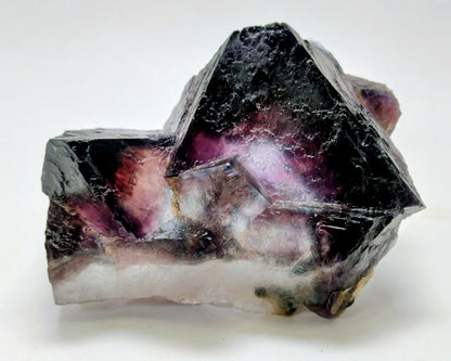 Mineral specimen with purple and black coloration on a white background