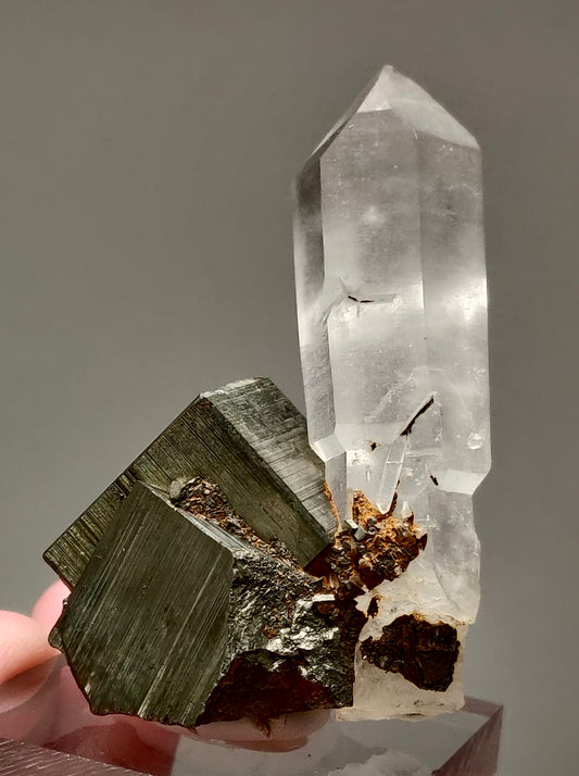 A crystal with a clear faceted top and a brownish metallic base, presumably pyrite, with visible patterns and hues.