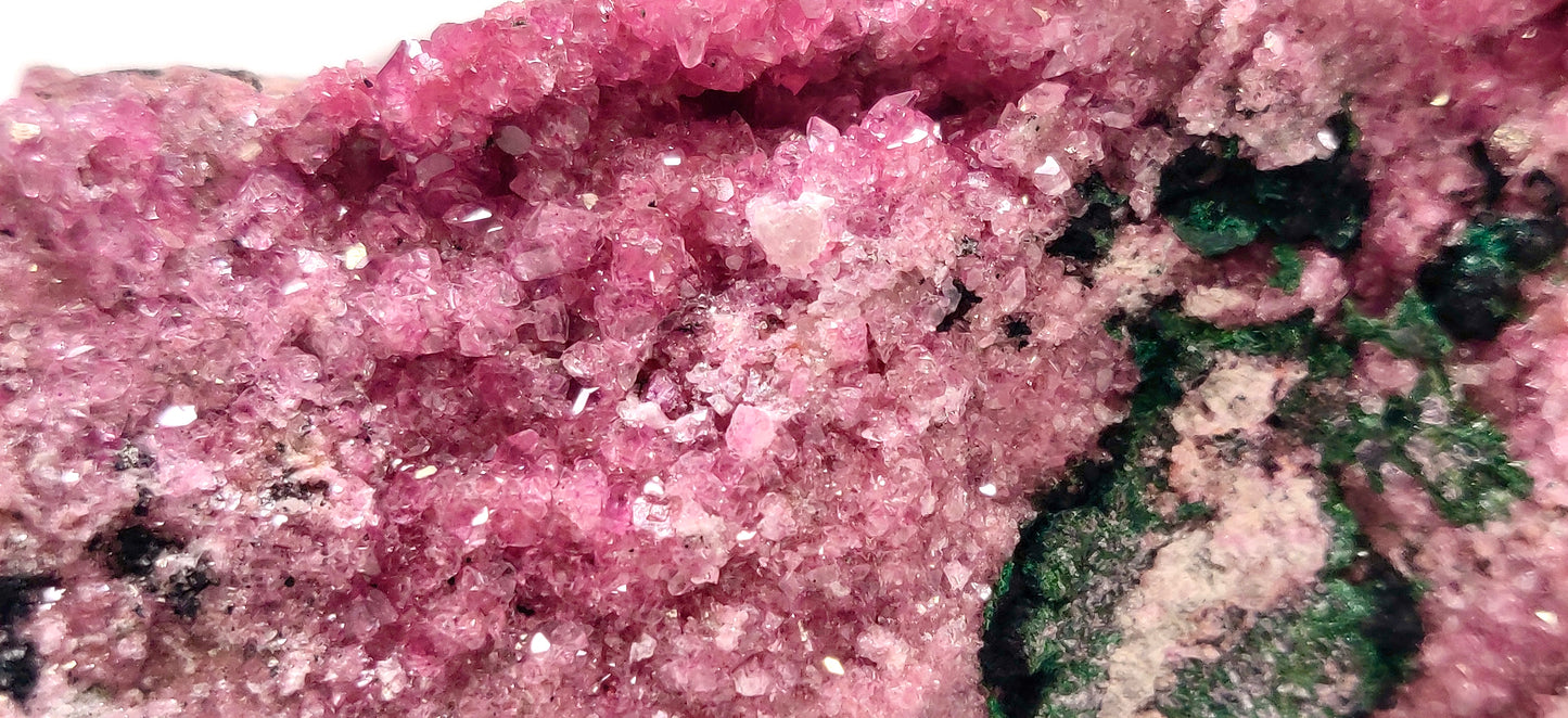 Close-up of pink crystal with green mineral on a white background