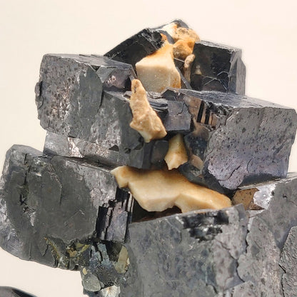 Mineral sample with dark and light gray crystals on a beige background