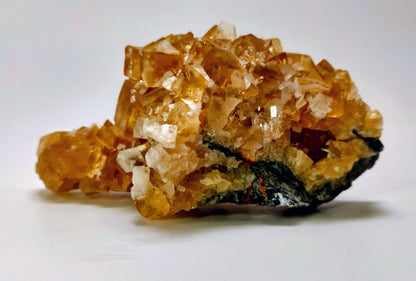 Mineral sample with clear and orange crystals on a white background