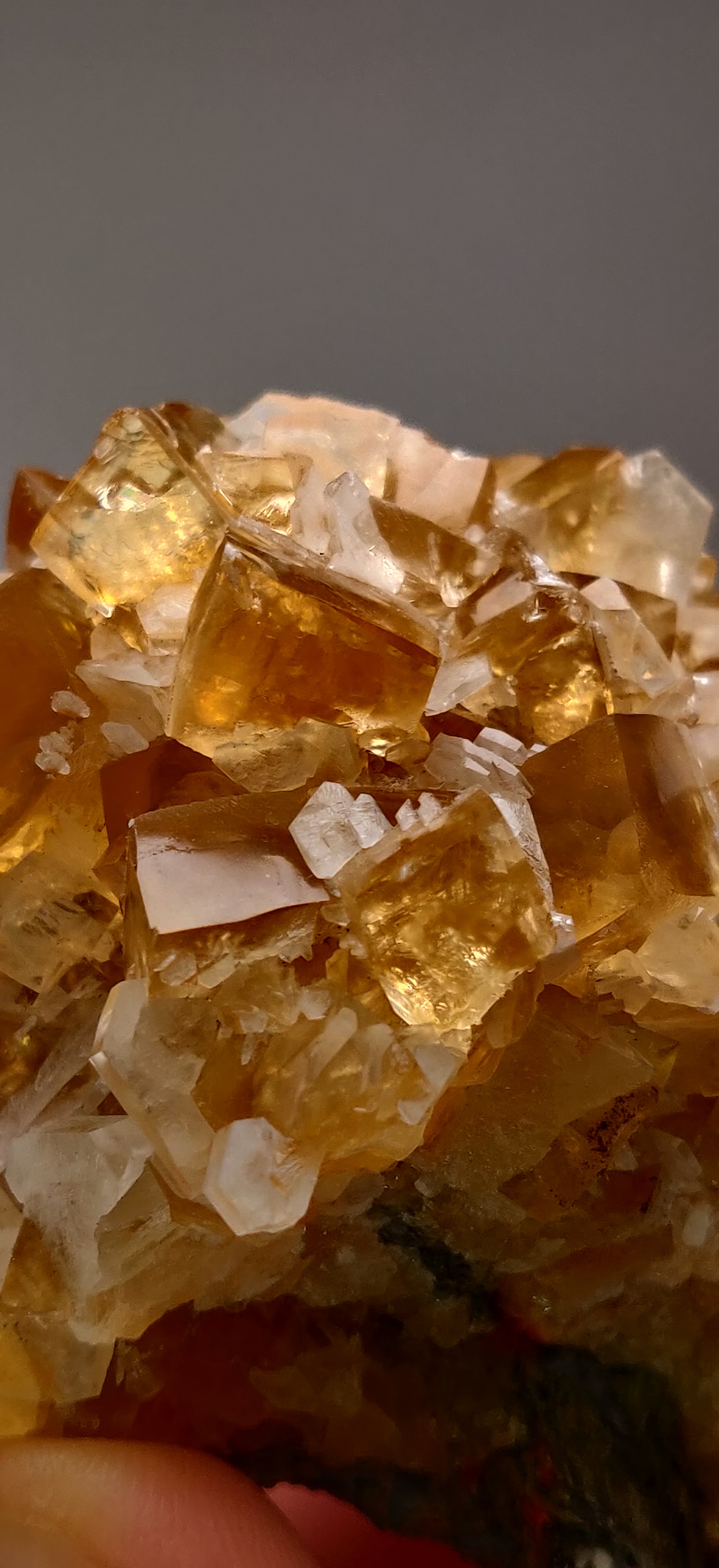 Close-up of a crystal cluster with yellow and white crystals on a gray background