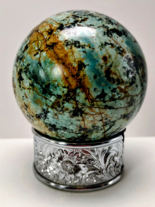 Marbled stone sphere on a decorative metal stand against a white background