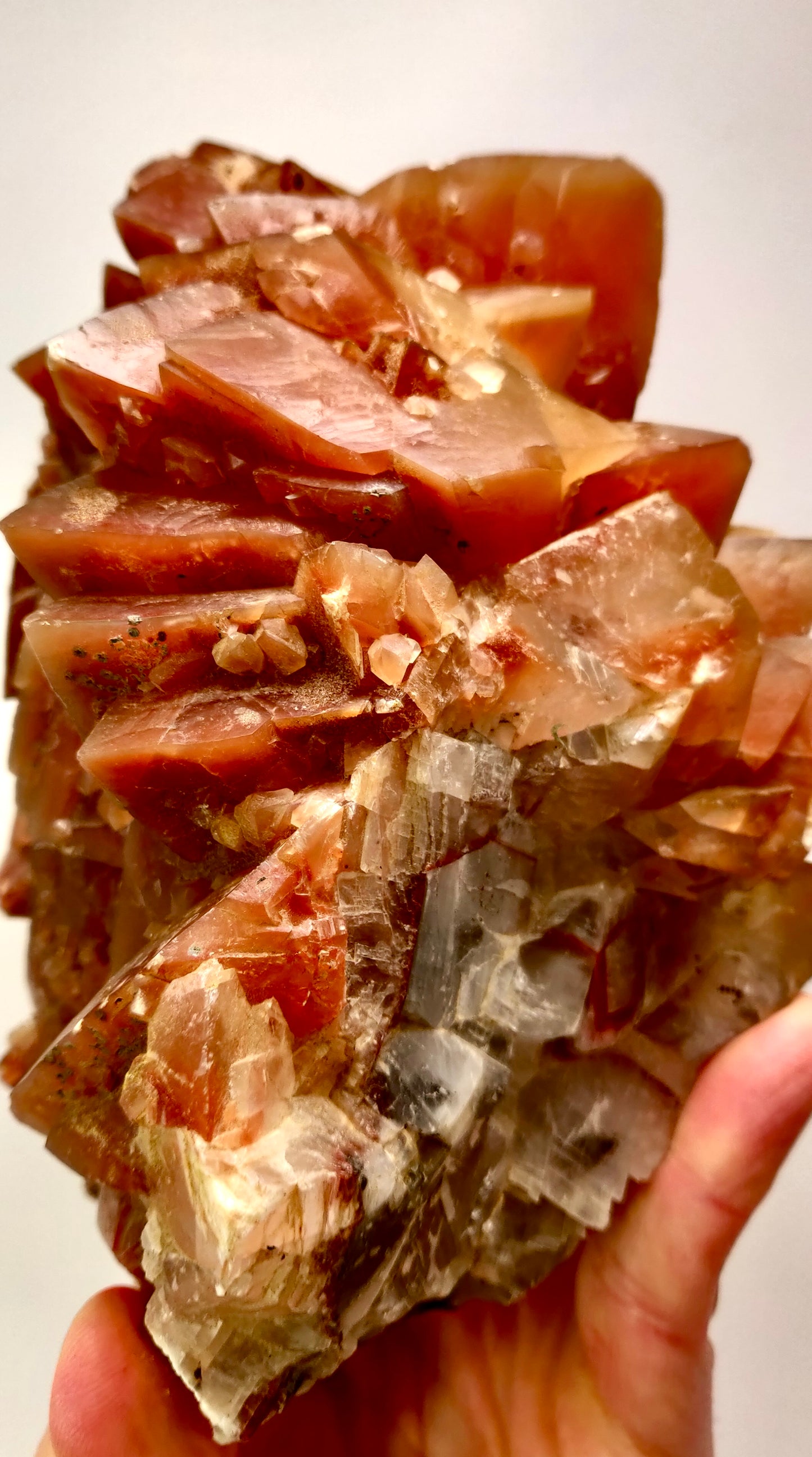 Mineral sample held by a hand with a white background