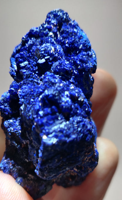 Blue crystal rock held in a hand against a neutral background
