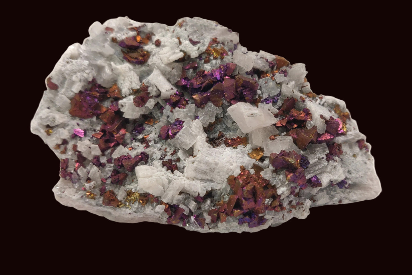 Iridescent rainbow chalcopyrite crystals on white rhombohedral calcite matrix from Baisha Mine, China.