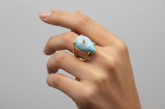 Gold ring with a large blue stone on a white background