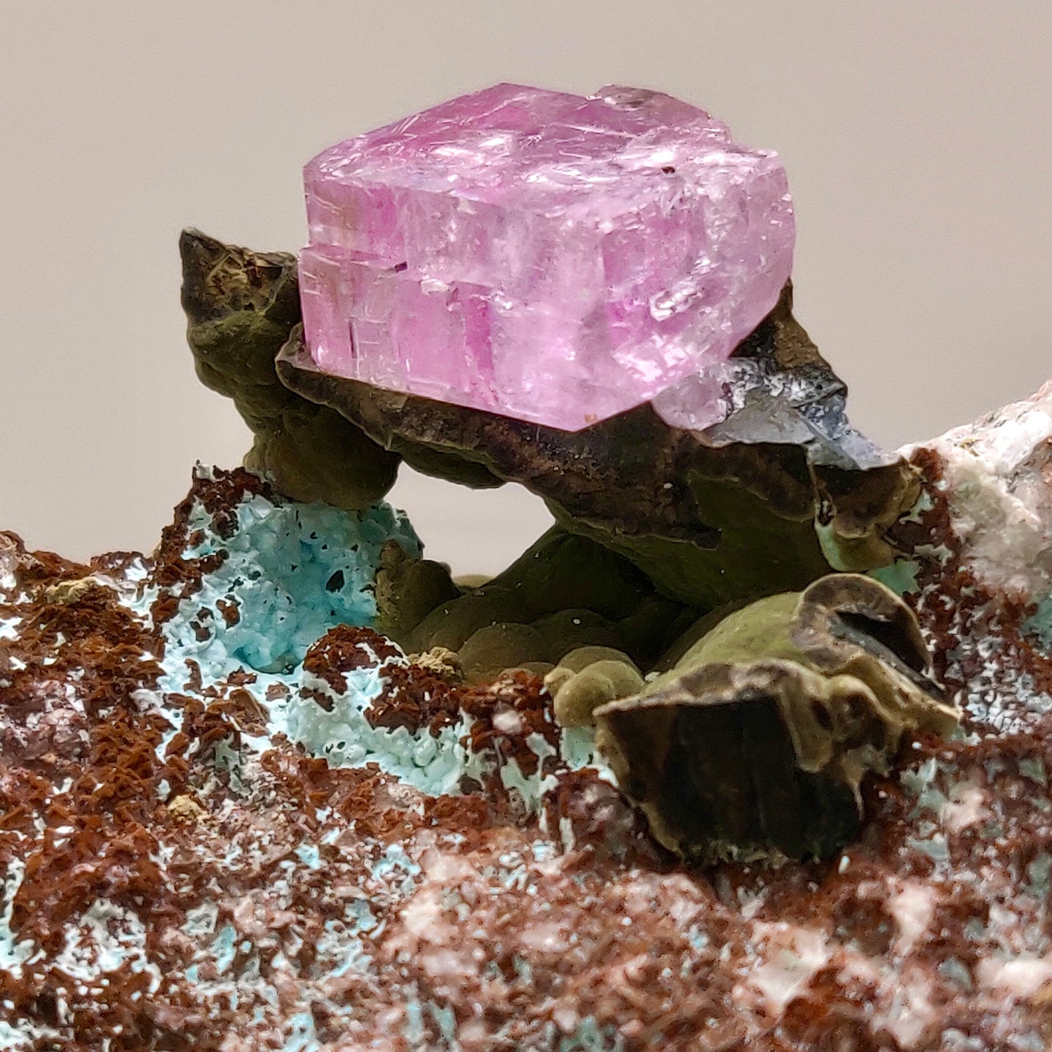 Pink crystal on a mineral rock with a neutral background