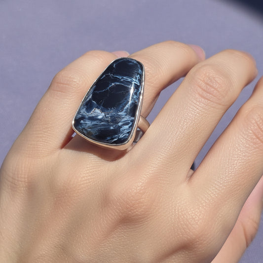 Blue stone earring on a clear stand against a purple background