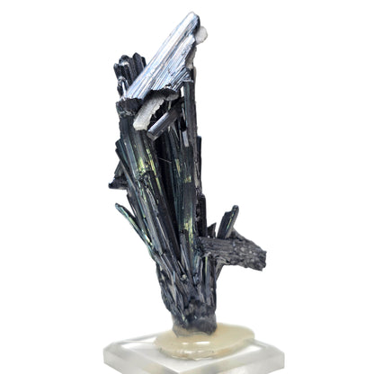 A natural mineral crystal cluster featuring dark metallic black and gray rods with iridescent green and blue sheen, mounted on a small beige stone base.